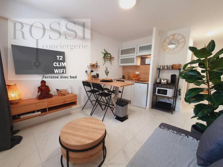 ein Wohnzimmer mit einem Tisch und einer Küche in der Unterkunft T2 Magellan Centre-ville - Clim Wifi Terrasse - ROSSIconciergerie - Linge inclus in La Grande-Motte