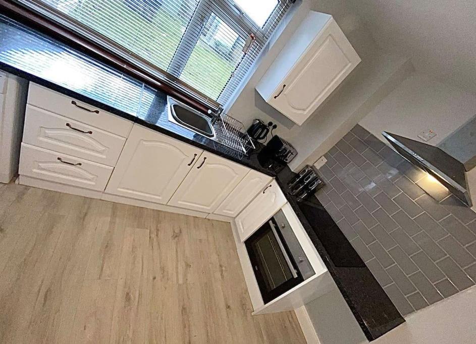 an empty kitchen with white cabinets and a window at Avondale Lodge in Sligo