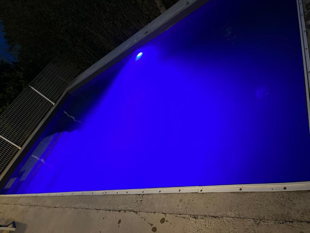 een groot blauw zwembad wordt 's nachts verlicht bij Villa climatisé avec piscine et jacuzzi in Carpentras