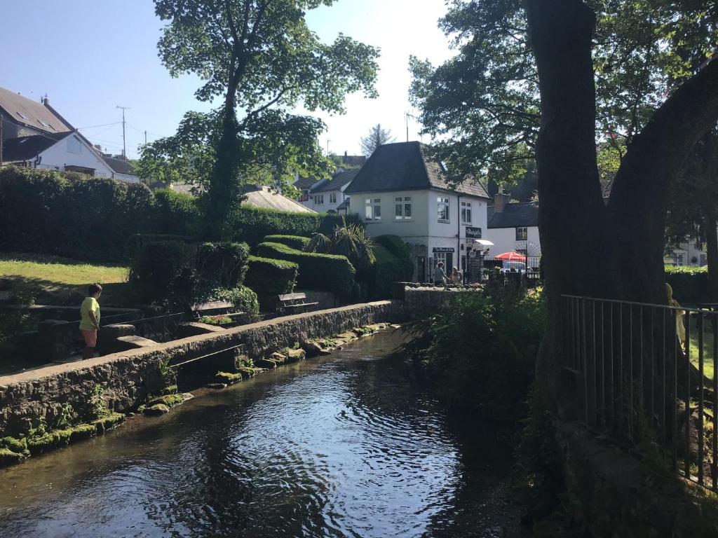 a man standing next to a river in front of a house at Dyserth Waterfalls apartment in Dyserth