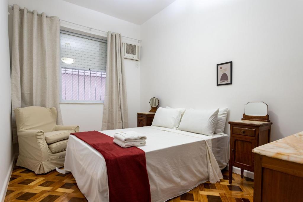 um quarto com uma cama, uma cadeira e uma janela em Gracioso no Leblon - 2 quartos - AP102 no Rio de Janeiro