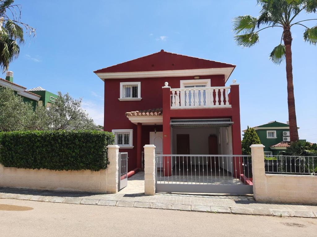 a red house with a white balcony and a palm tree at URBANIZACION MIRAMAR PENISCOLA in Peniscola