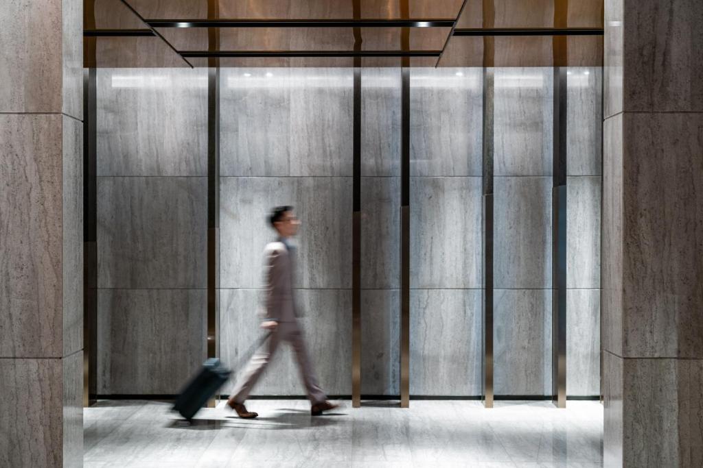 mężczyzna przechodzący przez budynek z walizką w obiekcie The G Shenzhen, A Tribute Portfolio Hotel w mieście Shenzhen