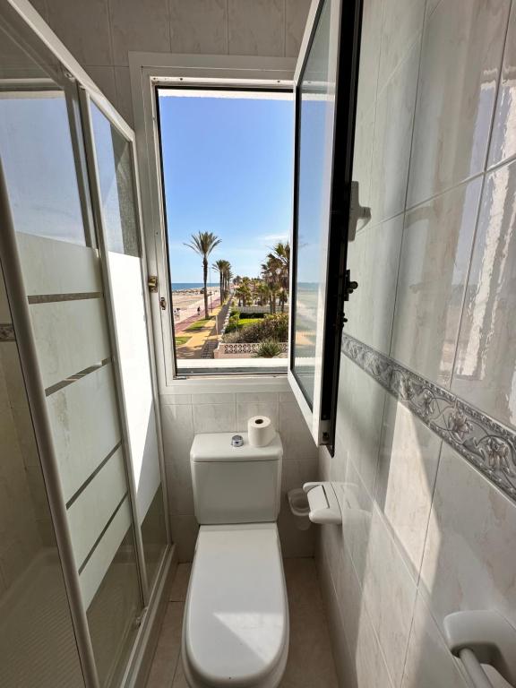 a bathroom with a toilet and a window with the ocean at La Vela Playa 1 in Roquetas de Mar