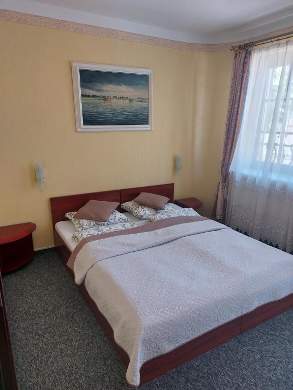 a bedroom with a large bed with a picture on the wall at Pensjonat Oleńka in Ustka