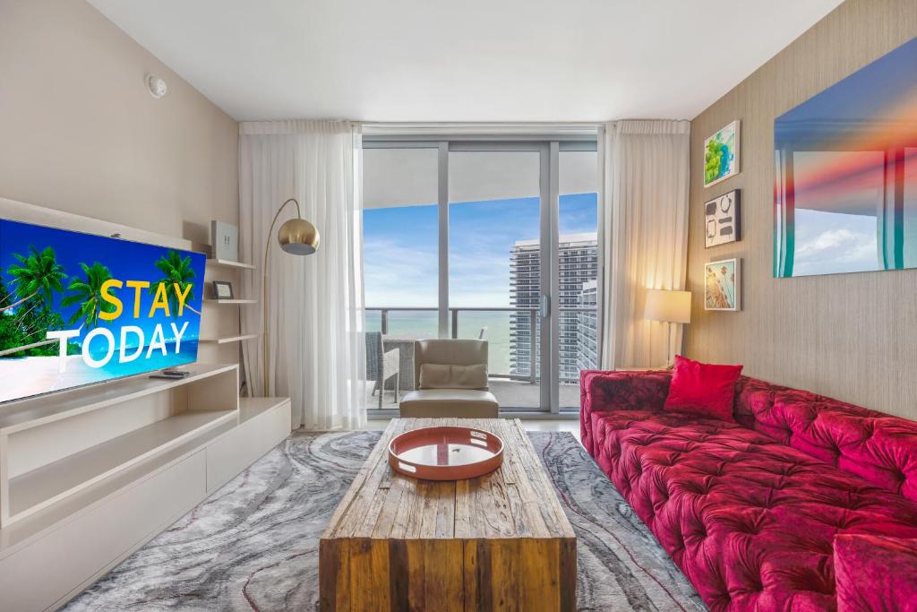 a living room with a red couch and a large window at Seashore Resort #3805 - 2 BEDROOM RIGHT ON THE BEACH DIRECT OCEAN-VIEW WITH AMENITIES ON THE ROOFTOP in Hollywood