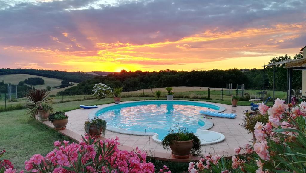 una piscina en un patio con una puesta de sol en el fondo en Les Hauts de Grazac en Grazac