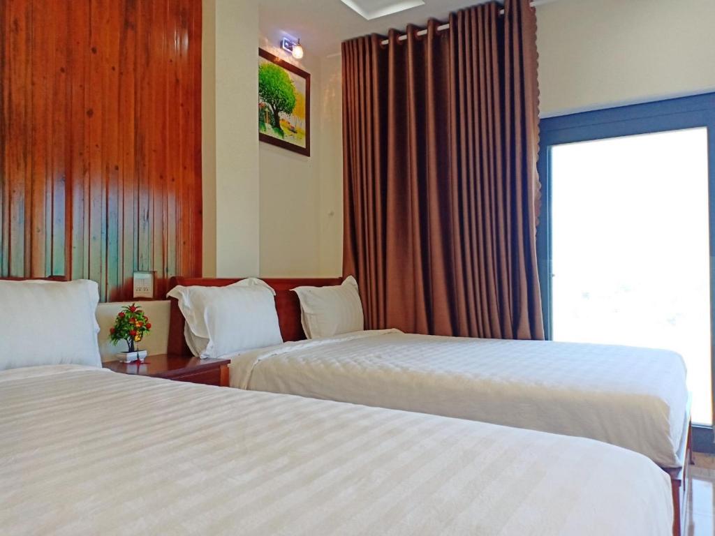 a hotel room with two beds and a window at GERBERA HOTEL in Quy Nhon