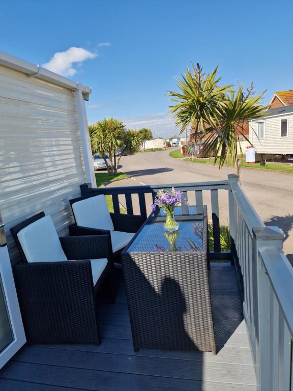 a patio with a table and chairs on a deck at Seaside Holiday Home Inside a Resort in Selsey