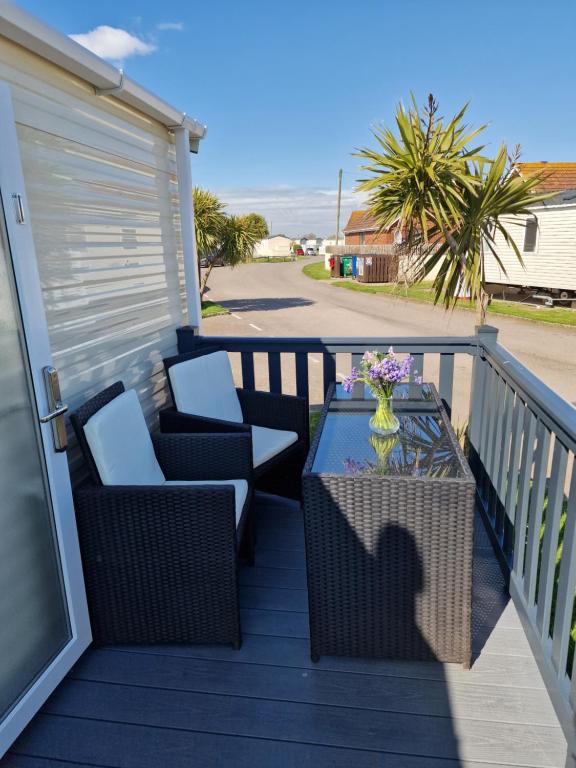 a patio with two chairs and a table on a deck at Seaside Holiday Home Inside a Resort in Selsey