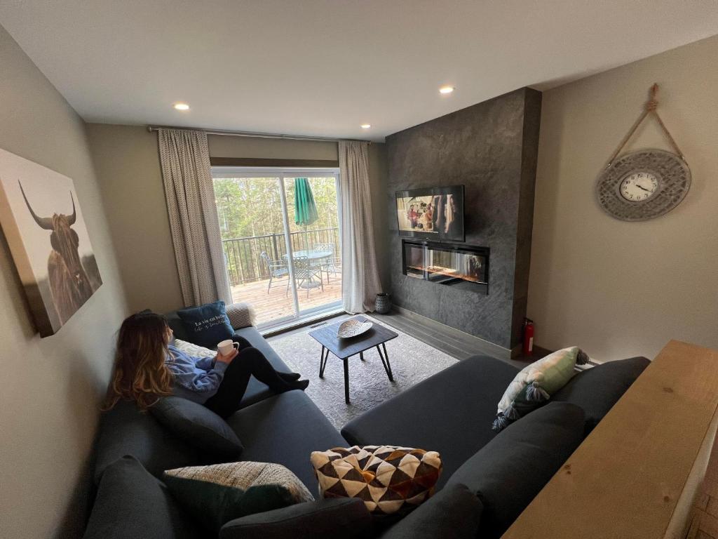 a woman sitting on a couch in a living room at Mont-Blanc - SPA - Plein air - Billard in Saint-Faustin