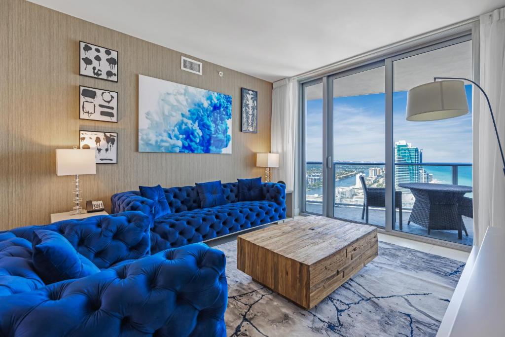 The Ultimate Resort #2904 - BEACHFRONT 2 BEDROOM APARTMENT WITH DIRECT OCEAN VIEW, ROOFTOP POOL, HOT TUB AND GYM في هوليوود: غرفة معيشة مع أريكة زرقاء ونافذة كبيرة