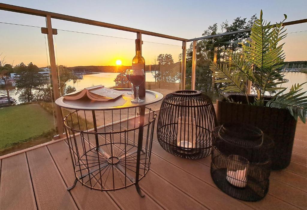 ein Balkon mit einem Tisch mit einer Flasche Wein darauf in der Unterkunft Perfect View - najlepszy widok w Iławie plus garaż podziemny, winda, Netflix in Iława