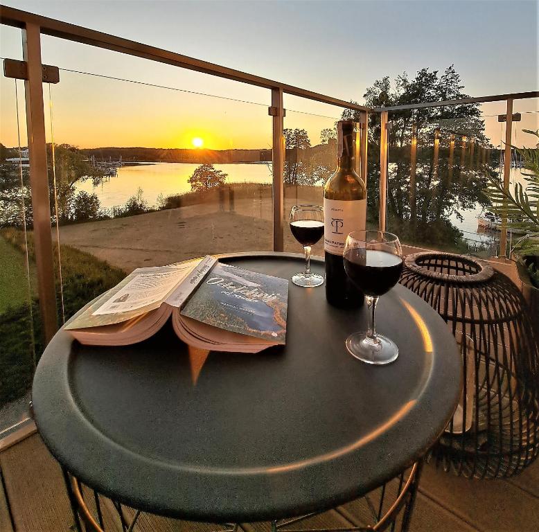 un tavolo con un libro e due bicchieri di vino di Perfect View Apartment a Iława