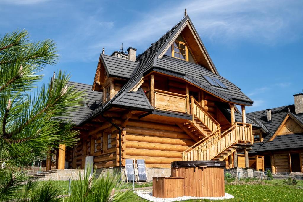 a log cabin with a black roof at Mountain Base - Dwupoziomowy apartament "Przy lesie II" z prywatnym jacuzzi w Kościelisku in Kościelisko