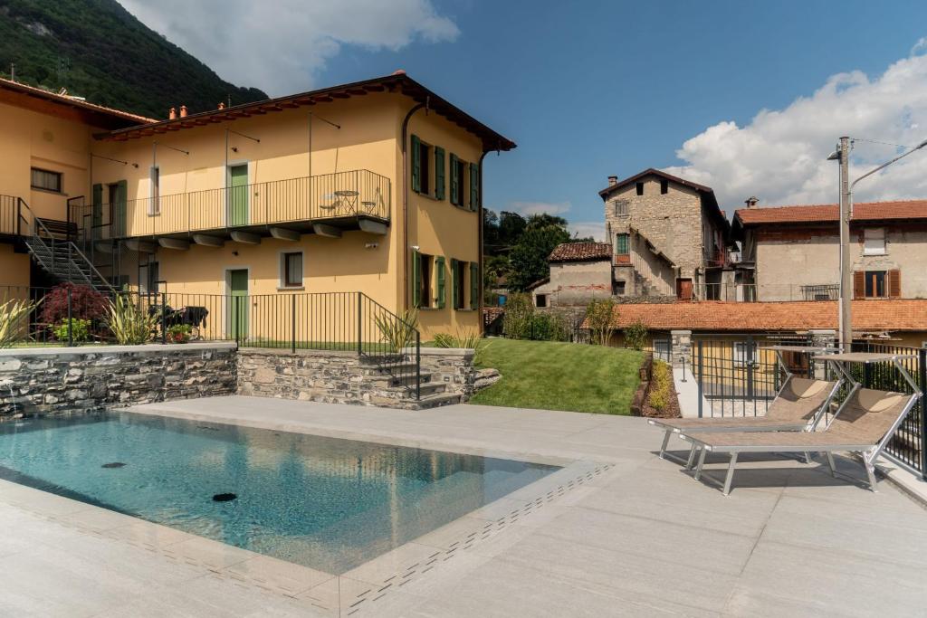 a swimming pool in front of a house with a chair at Corte Masnate - Grigio in Lenno