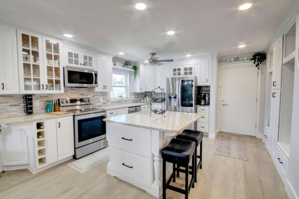 a kitchen with white cabinets and a island with stools at El Matador 539 - Third floor unit in Fort Walton Beach