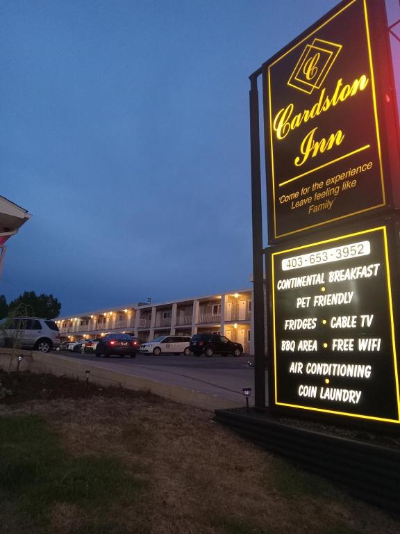 a sign for a building with cars parked in a parking lot at Cardston Inn in Cardston