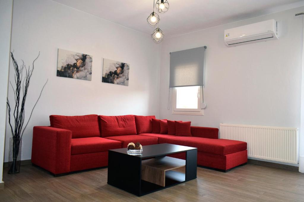 ein Wohnzimmer mit einem roten Sofa und einem Tisch in der Unterkunft Thea Home in Néa Karváli