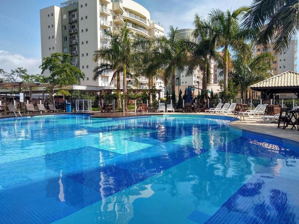 a large blue swimming pool with palm trees and buildings at Nautilus Paraíso Tropical - Vista ao Mar in Penha