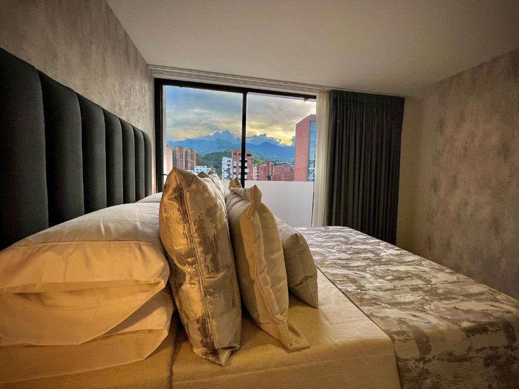 1 dormitorio con cama con almohadas y ventana en Apartamentos Gema by Cadissa en Medellín