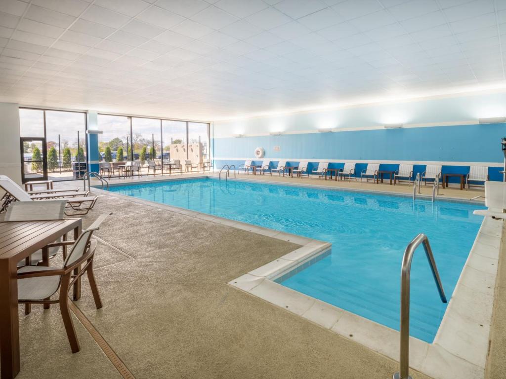 a large swimming pool with chairs and a table at Holiday Inn Chicago O'Hare - Rosemont, an IHG Hotel in Rosemont