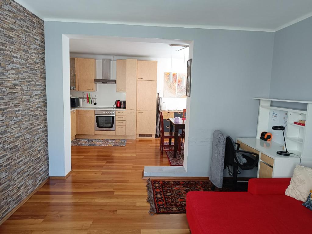 ein Wohnzimmer mit einem roten Sofa und einer Küche in der Unterkunft Moderne und schöne Wohnung in Graz
