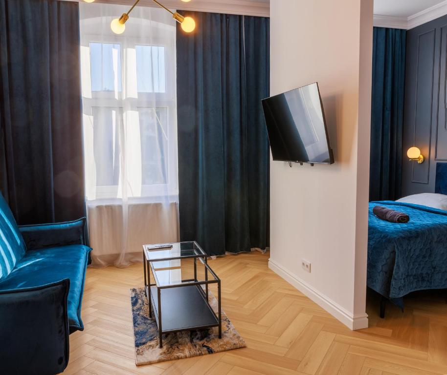 een woonkamer met een blauwe bank en een tv bij Apartament Zwycięzców 2 in Stargard