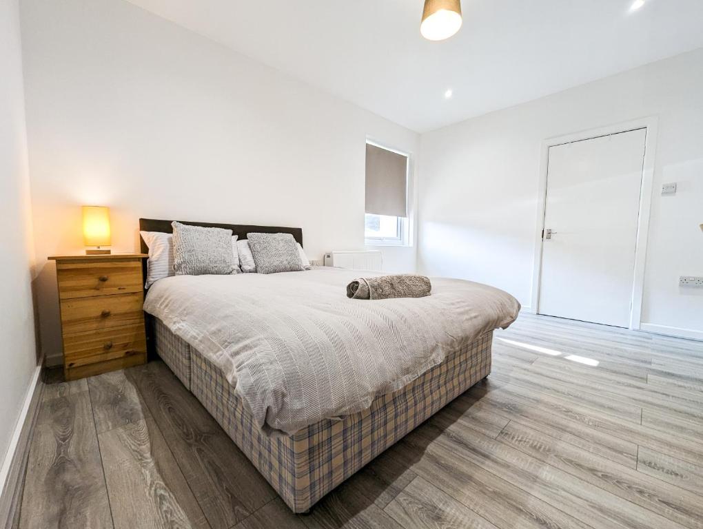 a white bedroom with a large bed and a dresser at Cozy Central Apartments - with Private Kitchens & Bathrooms in Portsmouth