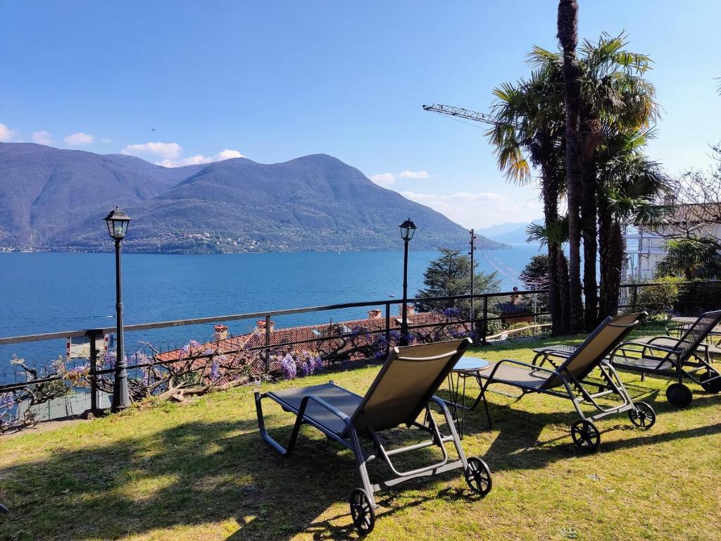 eine Gruppe von Stühlen auf dem Gras in der Nähe des Wassers in der Unterkunft Garden Hotel Primavera in Brissago