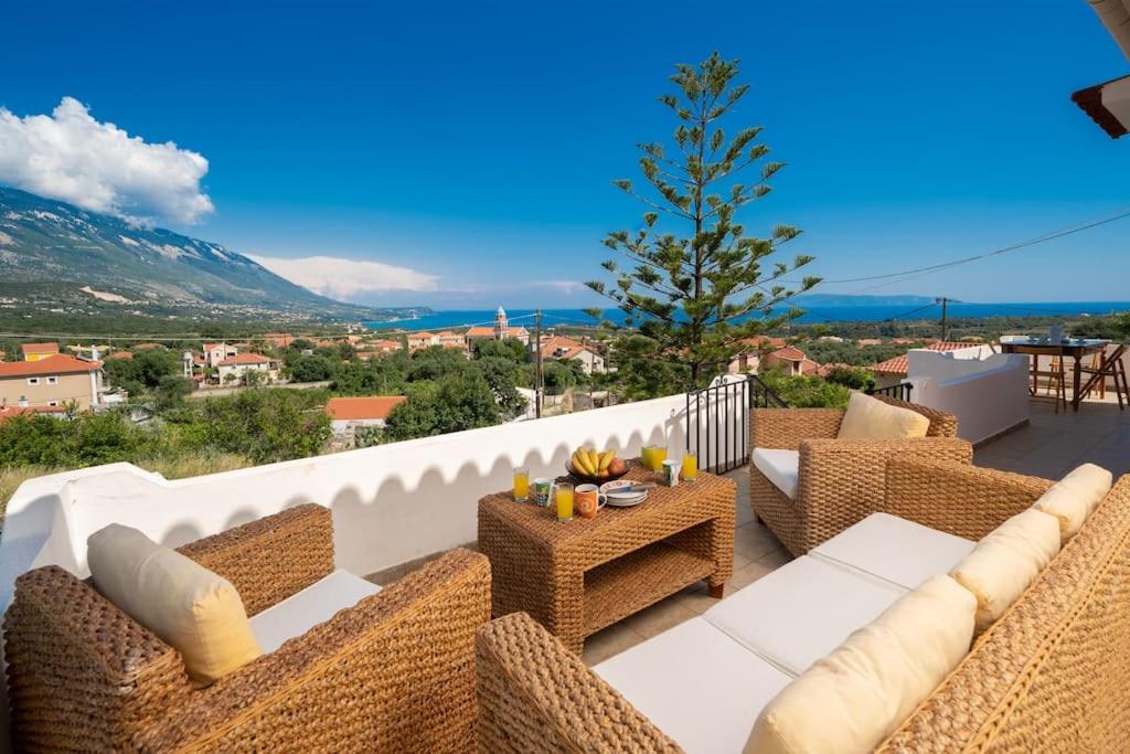 un patio con sillas de mimbre y mesas en un balcón en Villa Stunning Views, en Karavádhos