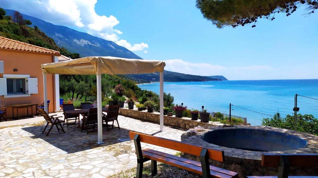 a patio with a bench and an umbrella and the ocean at NIKOS & SPIROS in Trapezaki