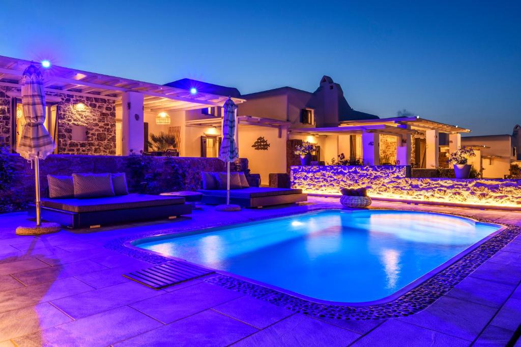 a swimming pool in front of a house at night at Aurora Mykonos Villas in Kalafatis