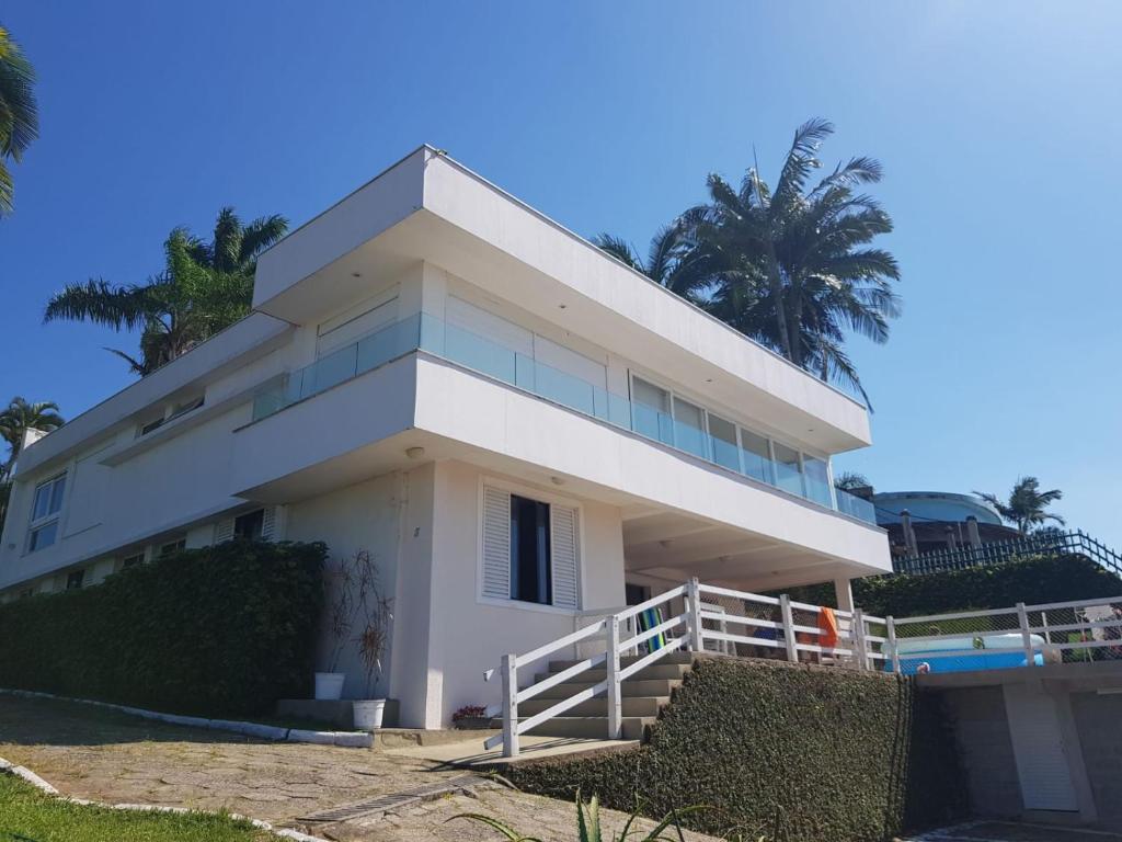uma casa branca com palmeiras ao fundo em Secret Spot Floripa em Florianópolis