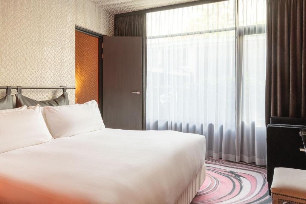 a bedroom with a bed and a large window at Apollo Hotel Amsterdam, a Tribute Portfolio Hotel in Amsterdam