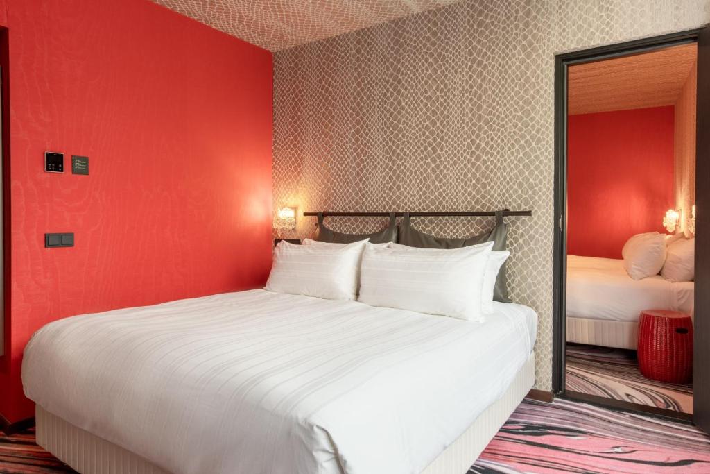 a bedroom with a large white bed with a red wall at Apollo Hotel Amsterdam, a Tribute Portfolio Hotel in Amsterdam