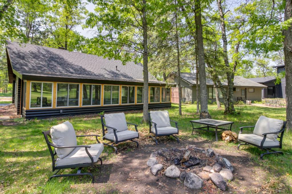 a group of chairs and a fire pit in front of a house at 1 Mi to Beach and Lake Breezy Point Cabin with Yard! in Pequot Lakes