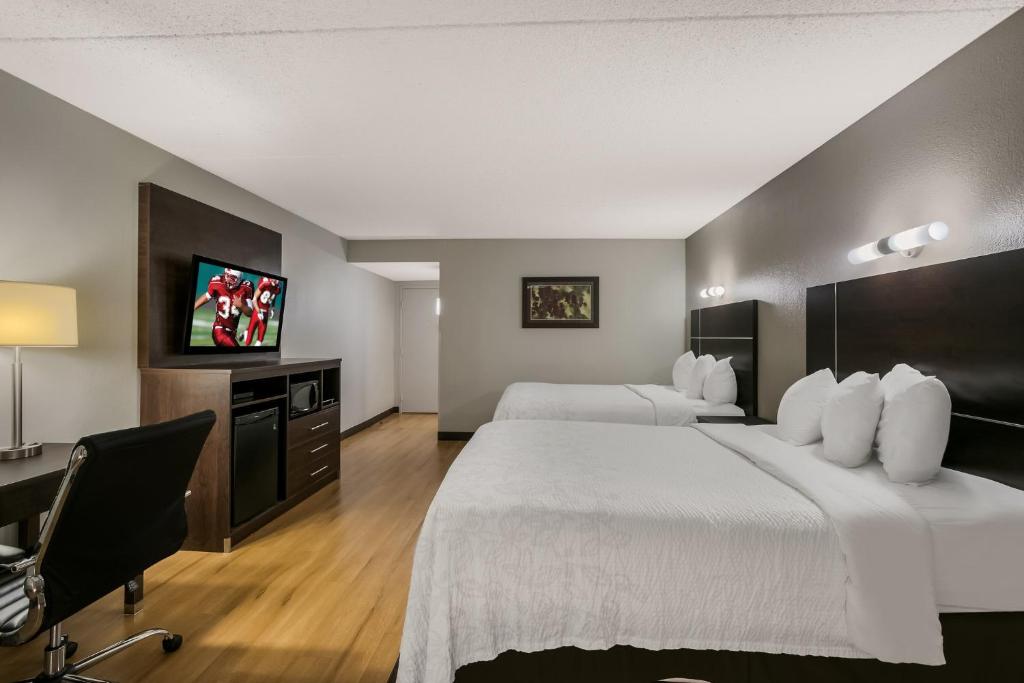 ノックスビルにあるRed Roof Inn PLUS+ & Suites Knoxville West - Cedar Bluffのベッド2台、デスク、テレビが備わるホテルルームです。