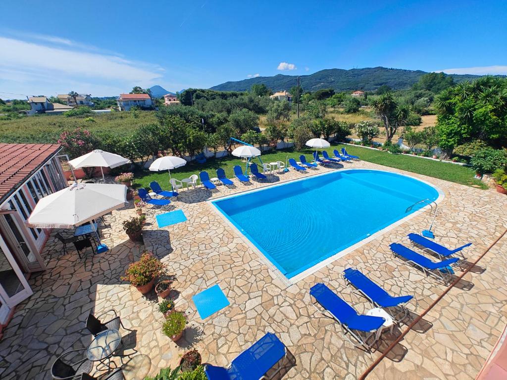 einen Blick über einen Pool mit Stühlen und Sonnenschirmen in der Unterkunft Elena Pool in Agios Georgios