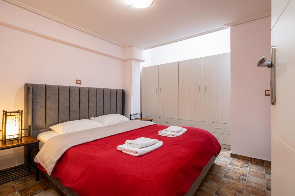 a bedroom with a red bed with two towels on it at Filippos Acharnes in Acharnes