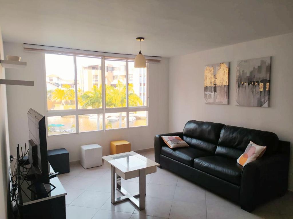 uma sala de estar com um sofá de couro preto e uma televisão em Confortable apartamento en Marina del Rey Lecheria em El Morro de Barcelona
