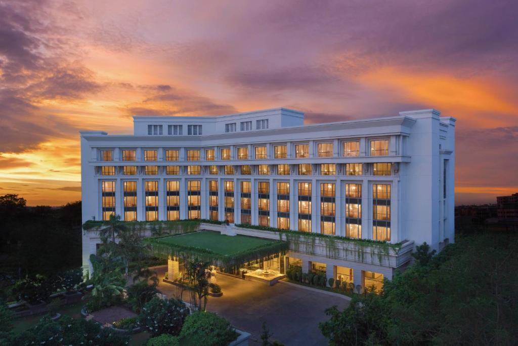 ITC Kakatiya, a Luxury Collection Hotel, Hyderabad في حيدر أباد: مبنى أبيض كبير مع غروب الشمس في الخلفية