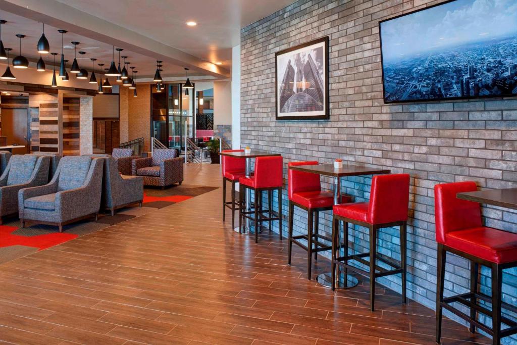 un bar con sillas rojas y una pared con TV en Four Points by Sheraton Detroit Novi, en Novi