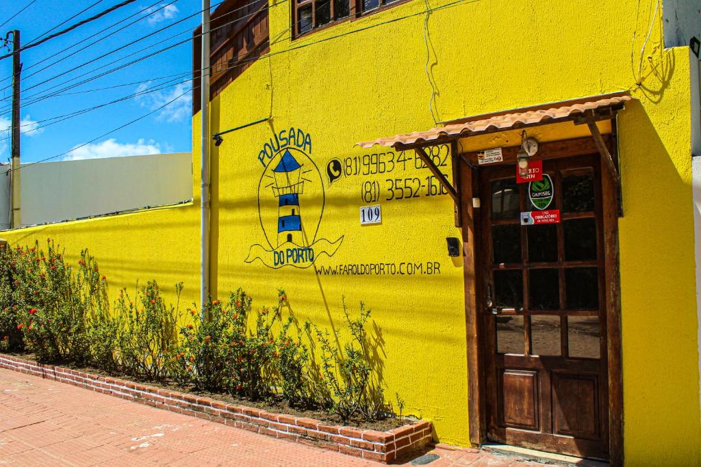 un edificio amarillo con una cara pintada en el costado. en Pousada Farol do Porto en Porto De Galinhas