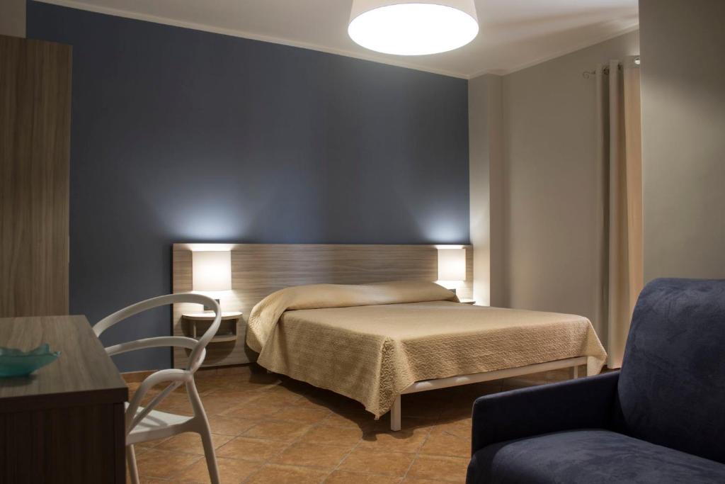 Incanto Luxury Rooms في لامبيدوسا: غرفة نوم بسرير وكرسي وأريكة