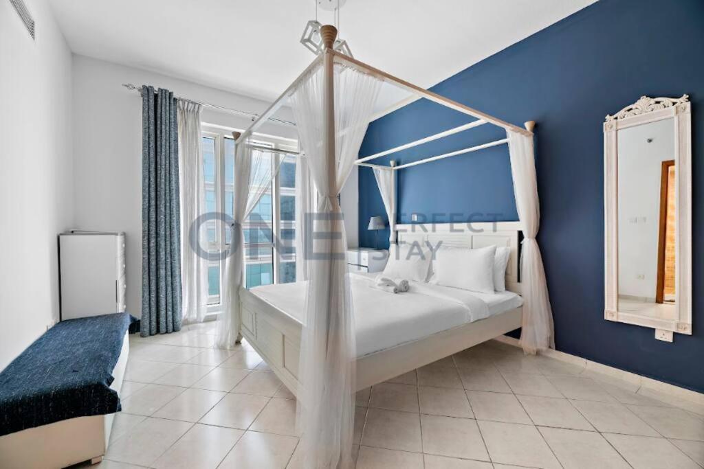 een slaapkamer met een hemelbed en een blauwe muur bij Lake View All Bills Included Fully furnished in Dubai