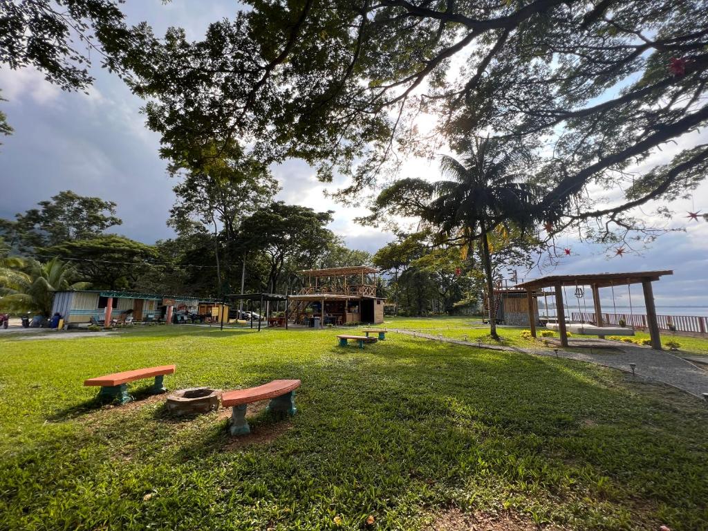 a park with three benches in the grass at Sunset Hut Hostel in Omoa