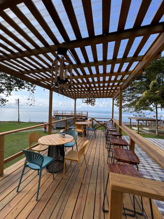 a wooden deck with tables and chairs on it at Sunset Hut Hostel in Omoa