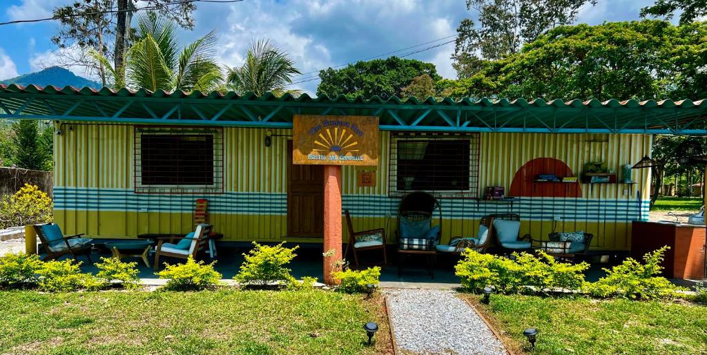 a yellow house with chairs in the yard at Sunset Hut Hostel in Omoa