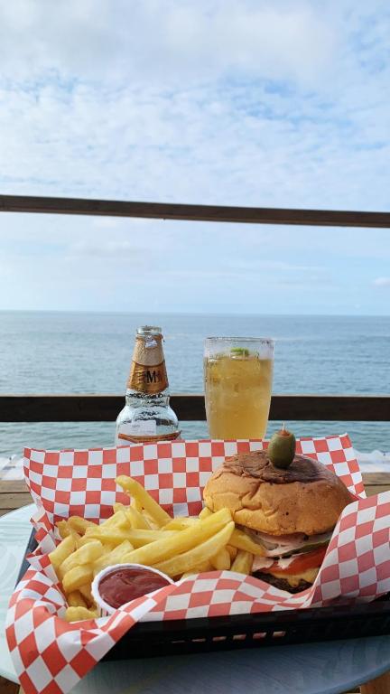 a sandwich and french fries on a table with a drink at Sunset Hut Hostel in Omoa